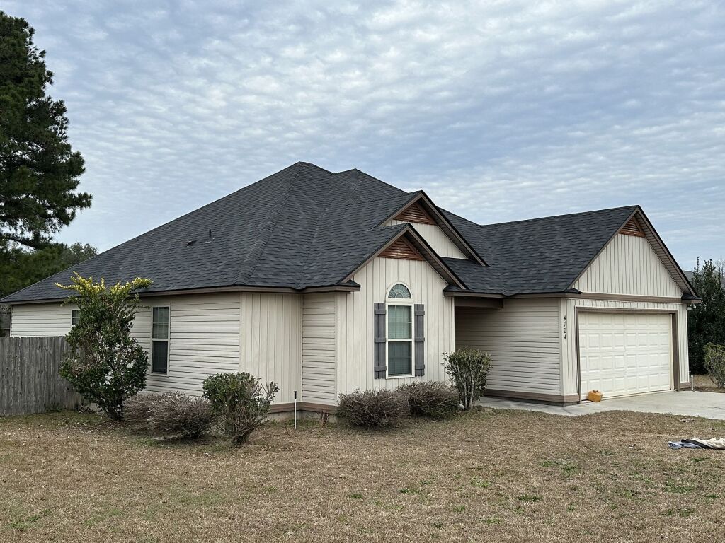 Single-story beige house with gray shingle roof and attached garage in residential neighborhood