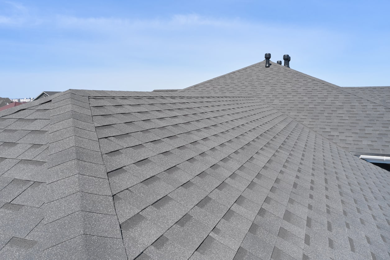 Grey shingle roof under blue sky.
