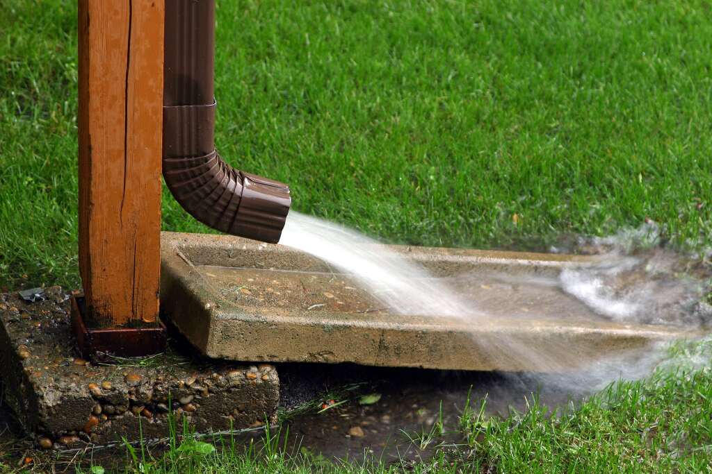 Water flowing from downspout onto grass.