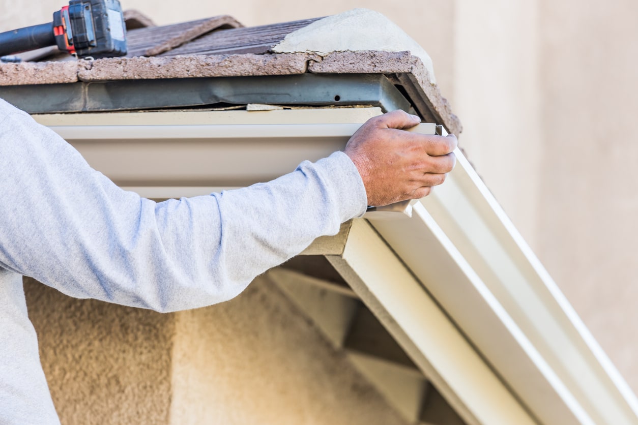 Person installing gutter on roof