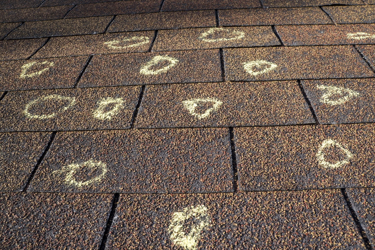 Roof shingles with chalk-marked circles indicating hail damage.