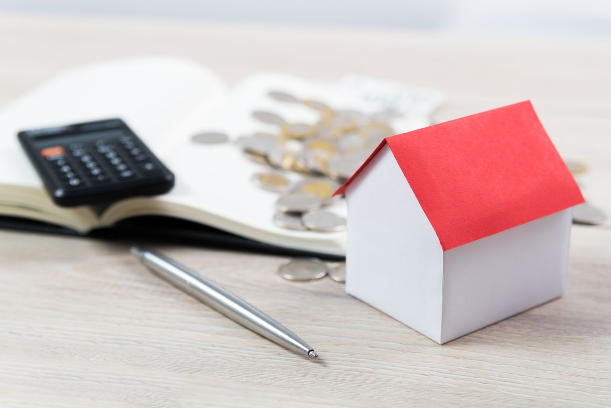 Model house with calculator and coins