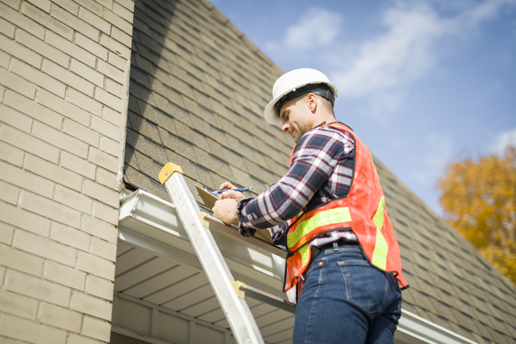 Worker repairing roof on ladder.