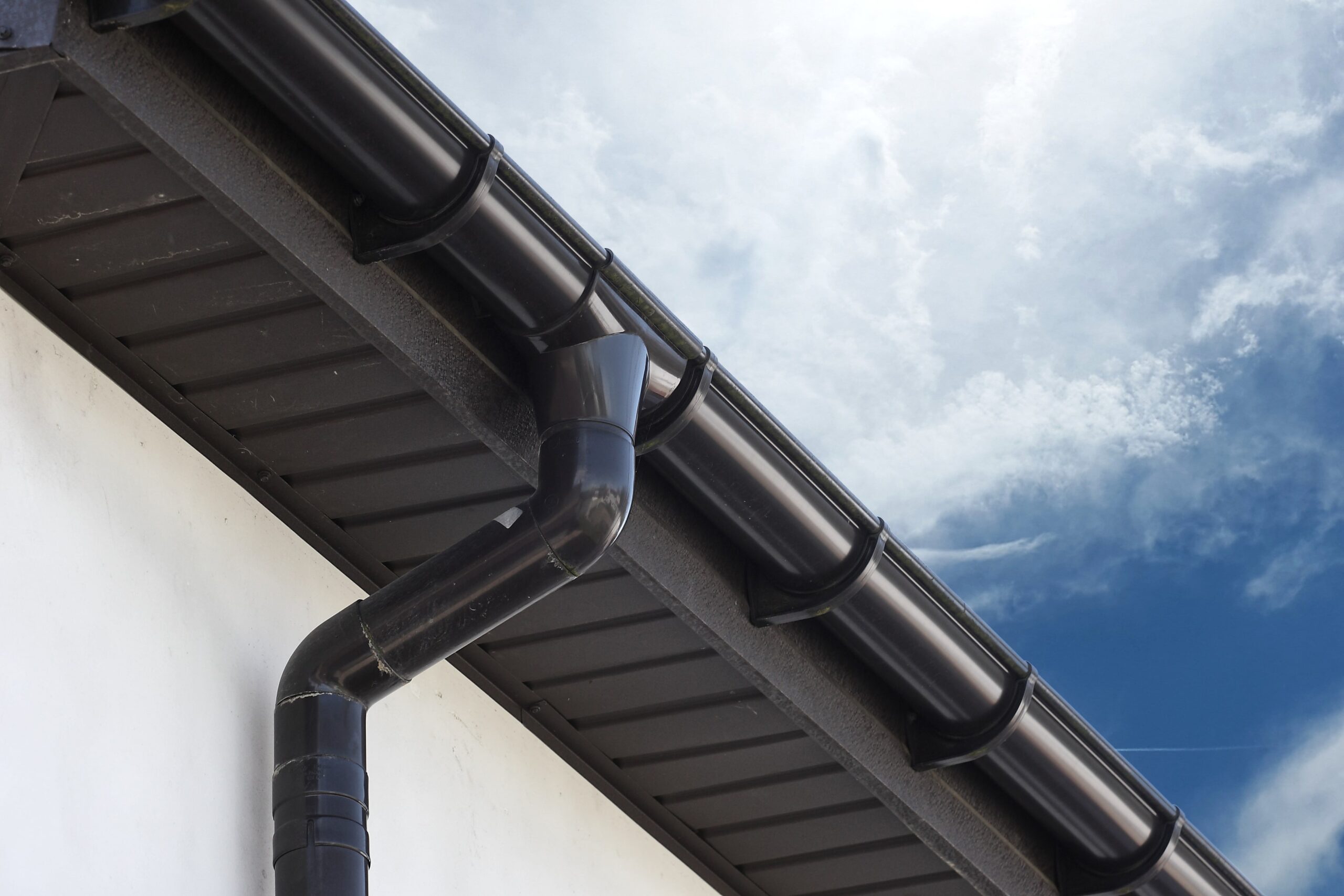 Black metal gutters against blue sky