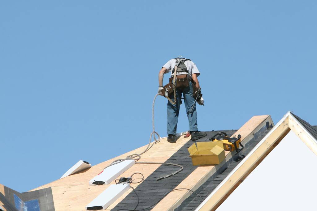 Worker installing shingles on roof.