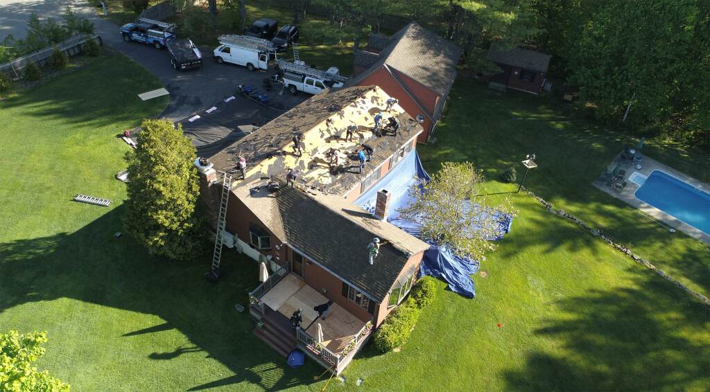 Workers replacing roof on house