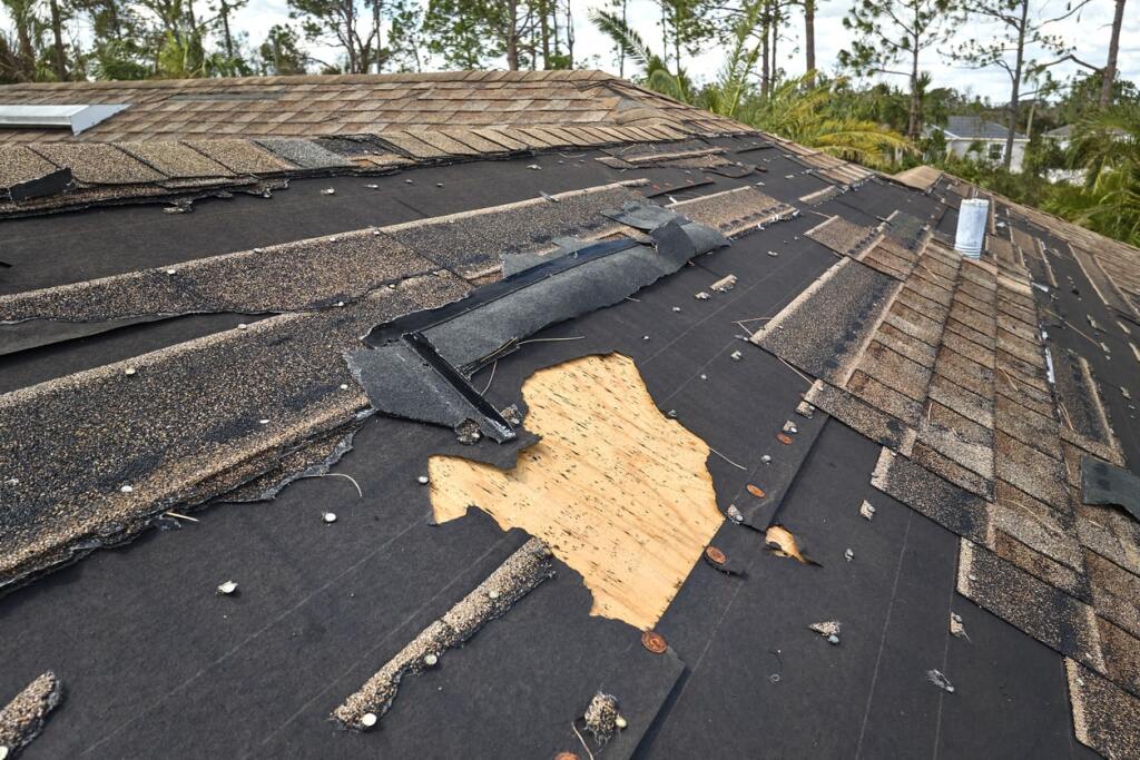 Torn shingles on damaged roof